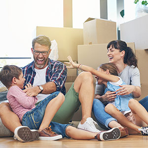 family sitting on floor of new home with packing boxes behind