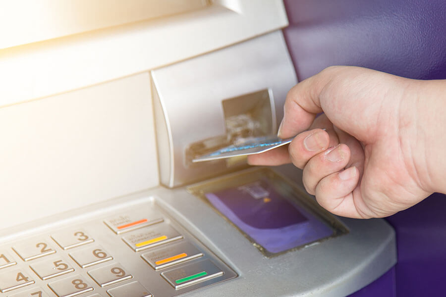 close up of person inserting debit card into an ATM