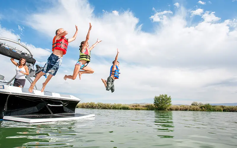 kids jumping off a boat into water
