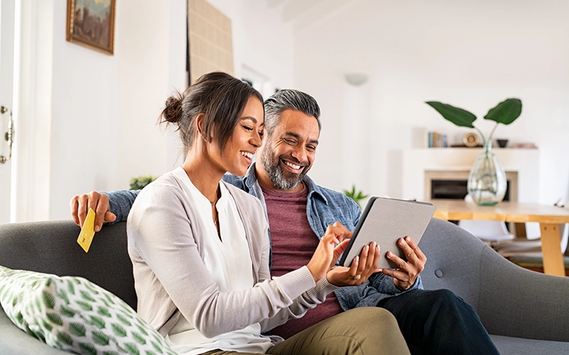 couple on couch with laptop and debit card