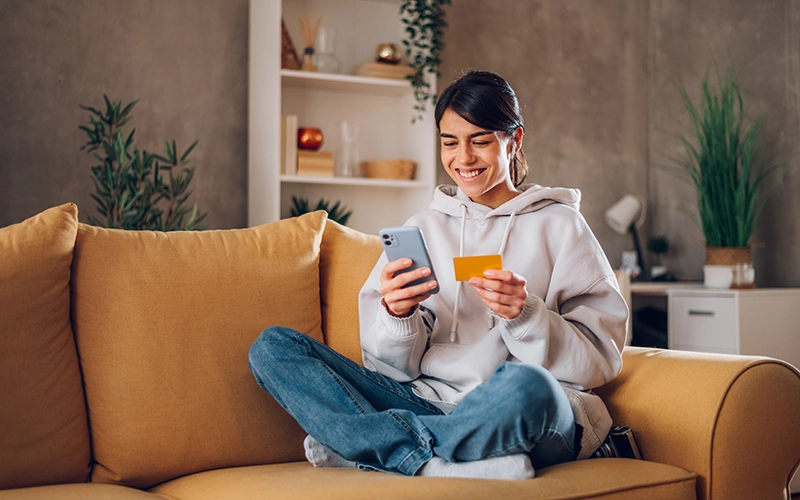 girl on sofa with credit card and phone