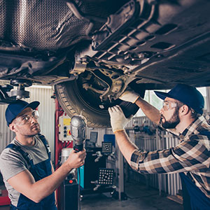 two men working on the underside of a vehicle