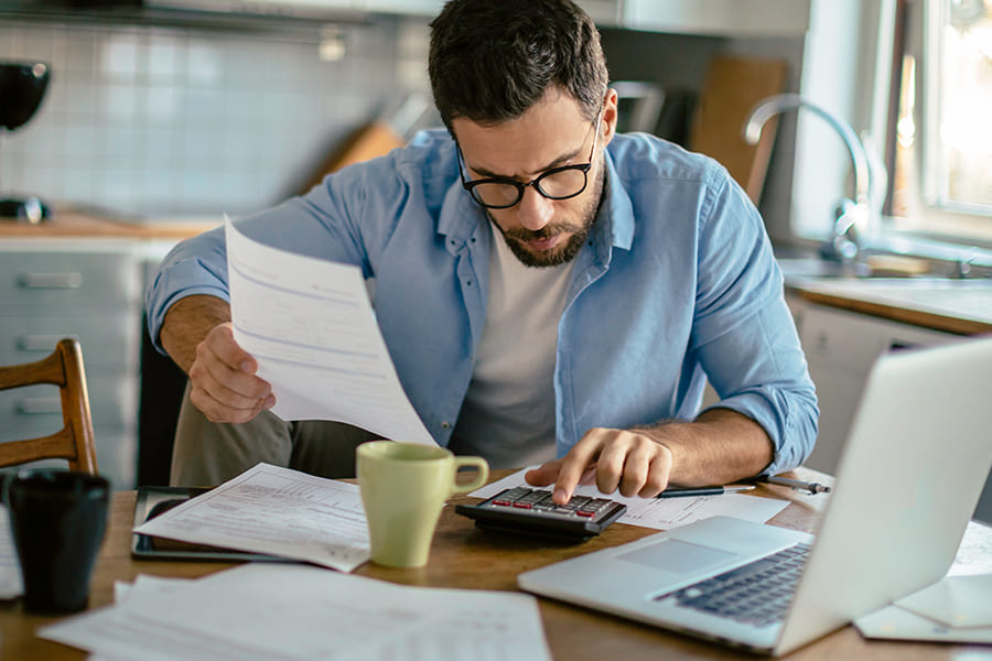 man using calculator to complete paperwork in home