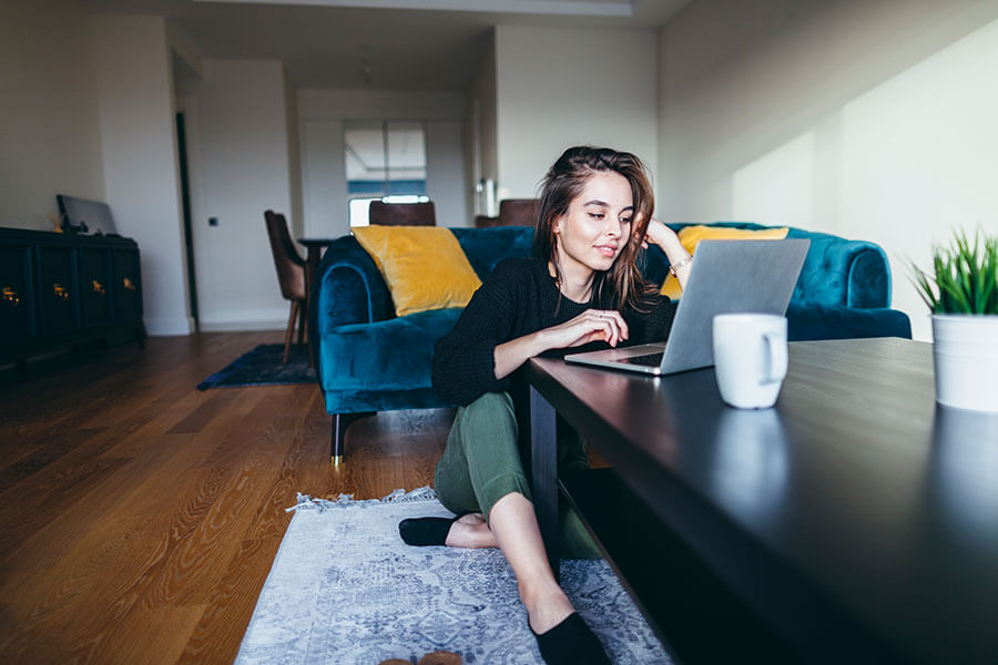 young girl sitting at coffee table in lounge wear looking at laptop computer